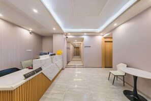 A hotel reception area with a reception desk, a waiting area with chairs, and a corridor leading to other rooms. - F1 Business Hotel (Shanghai Xinhua Hospital) (Shanghai)