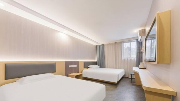 A hotel room with two beds, a desk, and a large mirror. - F1 Business Hotel (Shanghai Xinhua Hospital) (Shanghai)