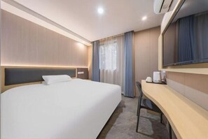 A hotel room with a large bed, a desk, a mirror, and a window with curtains. - F1 Business Hotel (Shanghai Xinhua Hospital) (Shanghai)