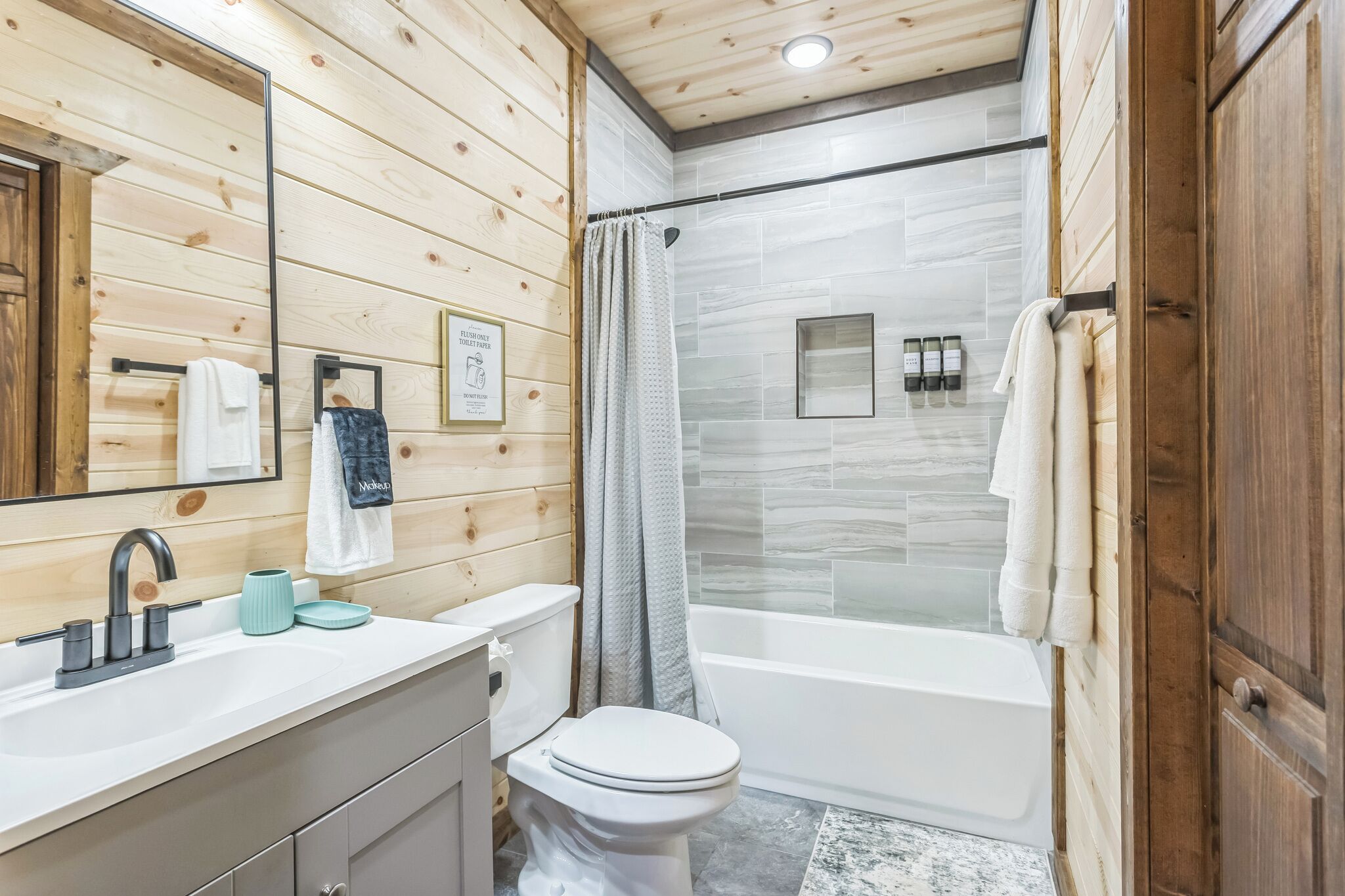A wooden-paneled bathroom with a white sink, toilet, and bathtub.
