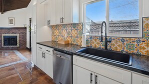 A modern kitchen with white cabinets, a black sink, and a colorful backsplash. - NEW! 3 Houses 2 the Sand-Spacious Gorgeous Remodel (Oxnard)
