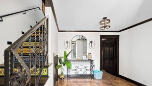 A staircase with ornate metal railings, a console table with decorative items, and a potted plant. - NEW! 3 Houses 2 the Sand-Spacious Gorgeous Remodel (Oxnard)