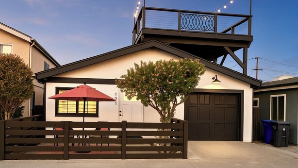 A modern house with a garage, a tree in front, and string lights on the roof.