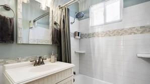 A bathroom with a white sink, vanity, and bathtub.