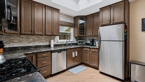 Una cocina moderna con armarios de madera, electrodomésticos de acero inoxidable, tragaluces y salpicadero decorado.