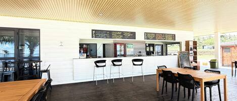 A restaurant with a wooden ceiling, bar area, and seating.