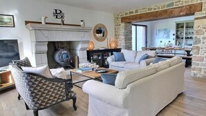 A living room with a fireplace, stone walls, and a sofa set. - La Marie Morgane - LEZARDRIEUX (LEZARDRIEUX)