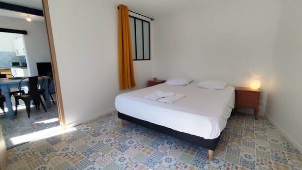 A bedroom with a bed, bedside table, and a mirror.
