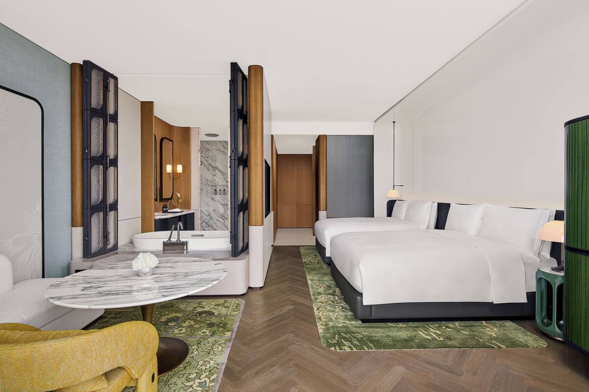 Ein Hotelzimmer mit Bett, einer Sitzecke, einem Esstisch, einem Badezimmer und Blick auf die Stadt.