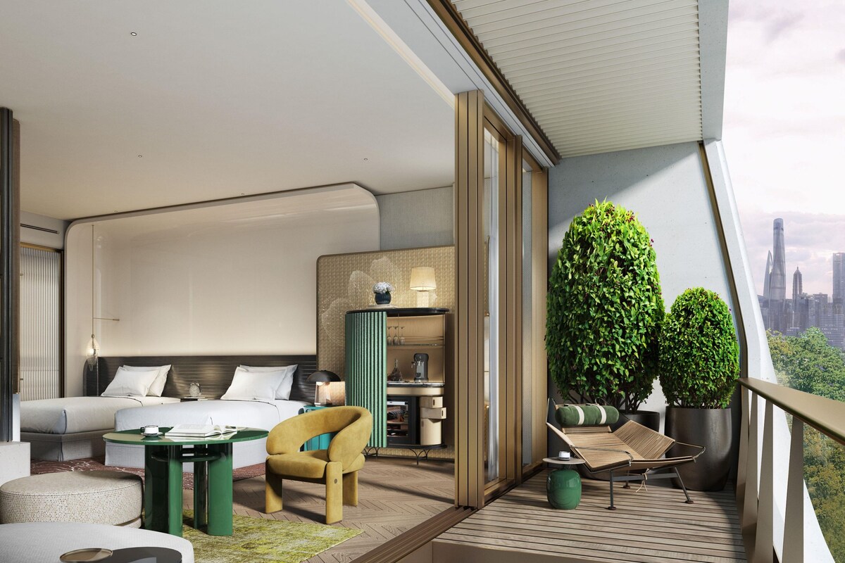 A modern hotel room with a balcony, a bed, a seating area, and a view of the city skyline.