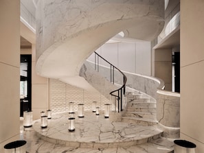 A grand marble staircase in a modern interior with a sleek railing and ambient lighting.