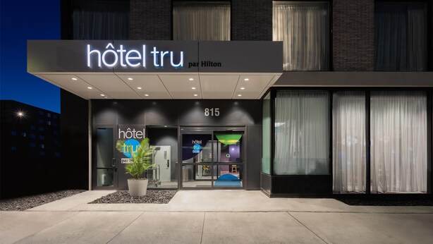Una entrada de hotel moderna con un cartel que dice "hôtel tru par Hilton" y el número "815".