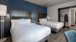 Una habitación de hotel con dos camas, un escritorio, una silla, un armario y un espejo.