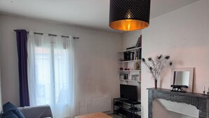 Una sala de estar con un sofá, una mesita de madera, un mueble para televisión, una chimenea y una estantería.