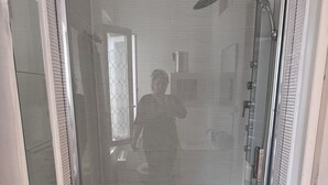 Cabina de ducha con paredes de vidrio y dos duchas de mano.