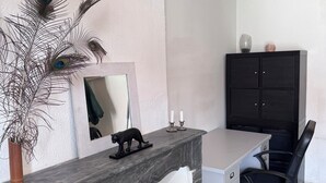 Un espacio de oficina moderno con un escritorio de mármol, una silla de oficina negra y una decoración con plumas de pavo real.