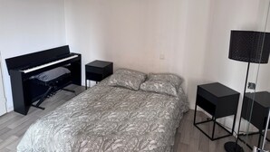 Un dormitorio con cama, piano, lámpara de pie y una mesita.