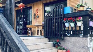 A wooden building with a staircase leading to a door, potted plants, and a red lantern. - Donghai Fishing Village Ganhai Renjia Guest House (Shengsi)