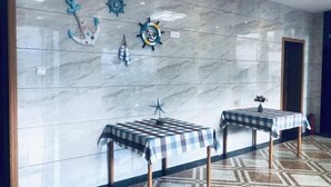 A hotel lobby with a marble wall, two checkered tables, and nautical-themed wall decor. - Donghai Fishing Village Ganhai Renjia Guest House (Shengsi)