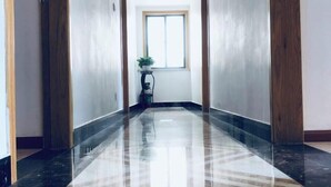 A hallway with a glossy marble floor, wooden paneling, and a window at the end. - Donghai Fishing Village Ganhai Renjia Guest House (Shengsi)