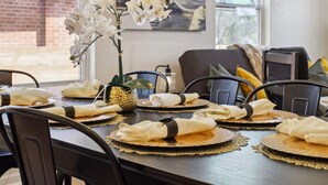 A dining table set with white napkins, gold placemats, and a vase of white orchids. - Sleek 4BR 3BA Urban Living w Downtown Views (San Antonio)