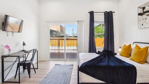 A modern hotel room with a bed, a desk, and a TV. - Sleek 4BR 3BA Urban Living w Downtown Views (San Antonio)