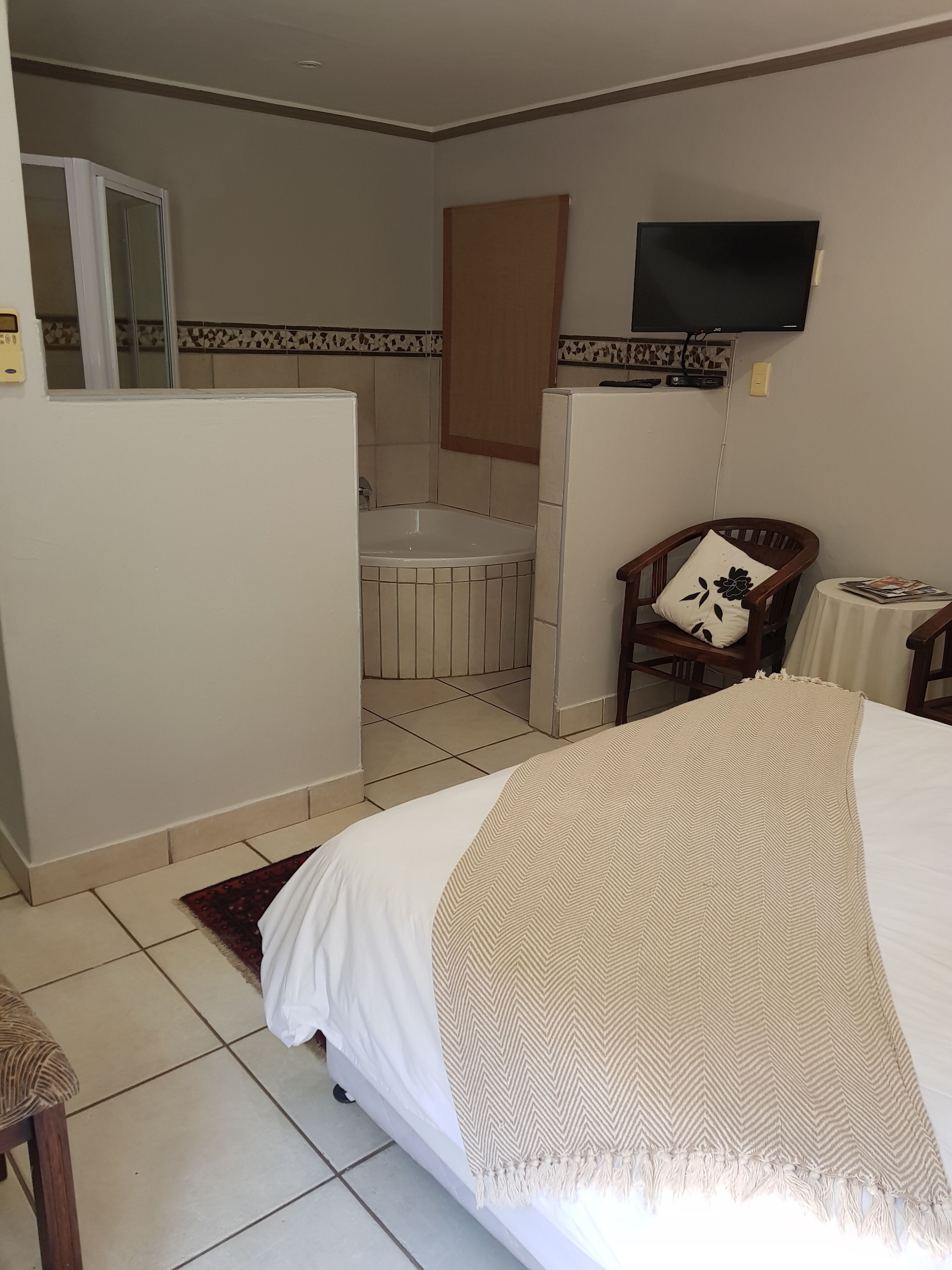 Habitación de hotel con cama, una silla, una mesita, televisor y baño.