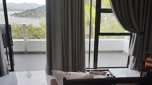 A bedroom with a bed, a table with a tray, and a view of a lake and hills through large windows. - El Shadai Guest House  Hartbeespoort (Hartbeespoort)
