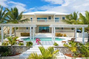 A two-story building with a pool, surrounded by palm trees and a white fence. - 5 Bedroom -Turquoise Dream Villa where you will find real Peace & Tranquility (Long Bay)