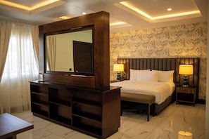 A hotel room with a large mirror, a bed with two pillows, a bedside table, and a nightstand with a lamp. - Hotel Hacienda Aguacaliente (Tijuana)