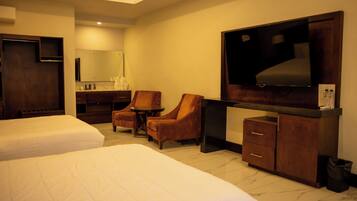 Habitación de hotel con dos camas, un escritorio, dos sillas, un televisor y un espejo.