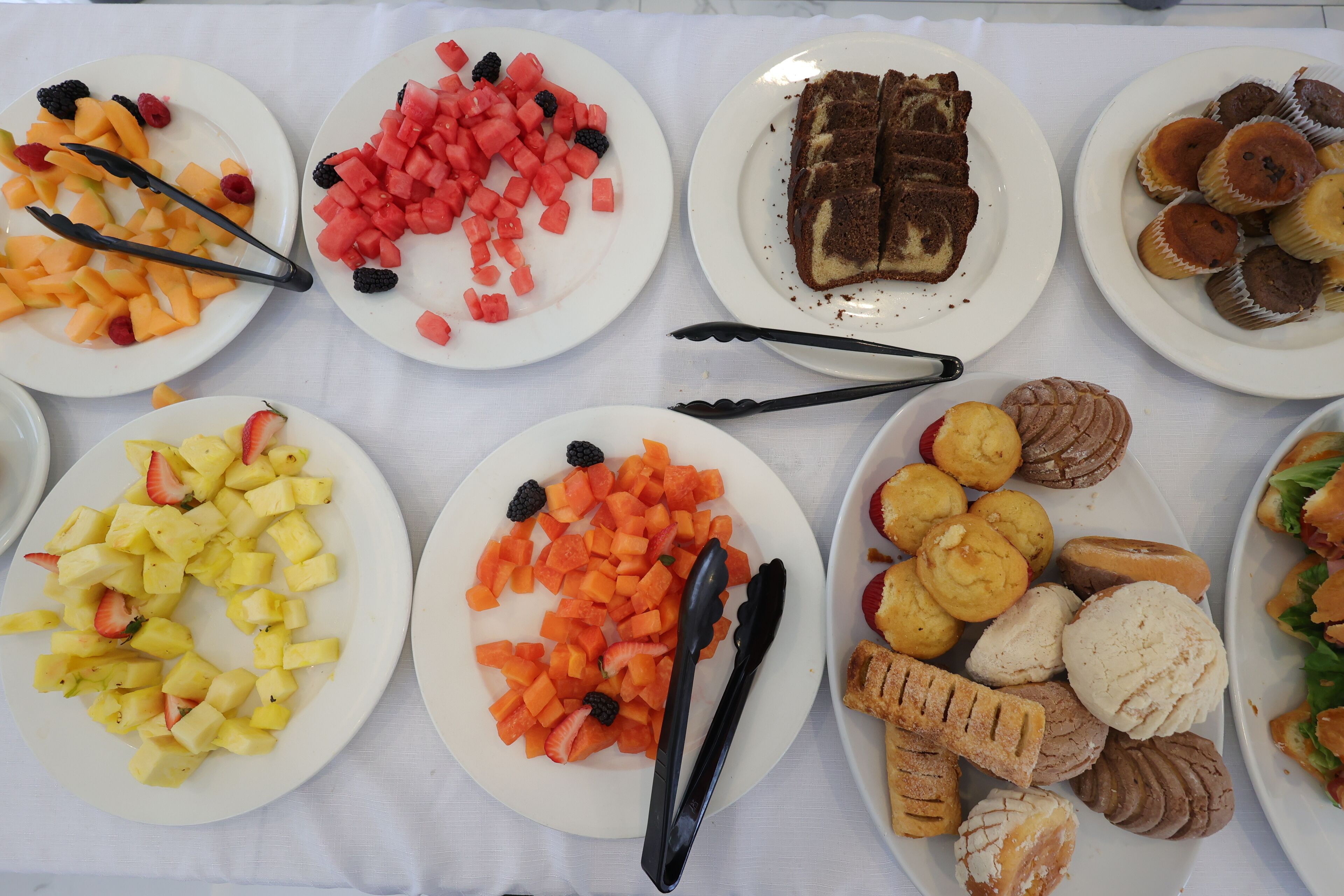 A table with various food items including fruits, pastries, and sandwiches.