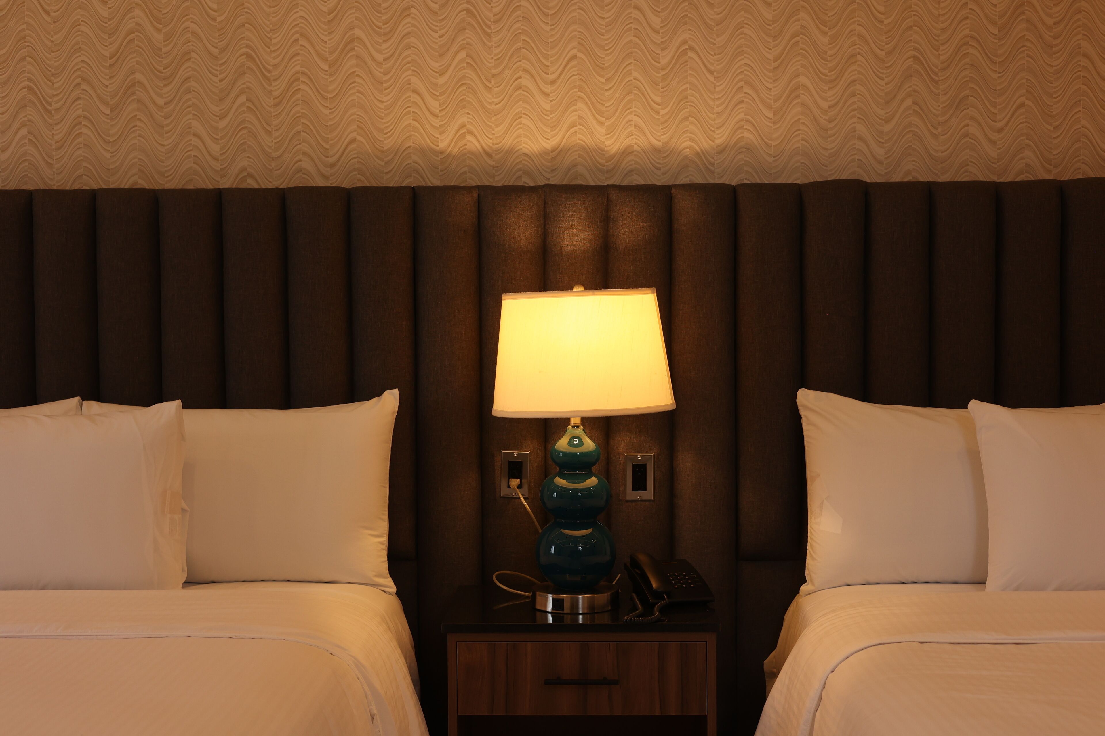 Ein Hotelzimmer mit zwei Betten, einem Nachttisch mit Lampe und einem Telefon.