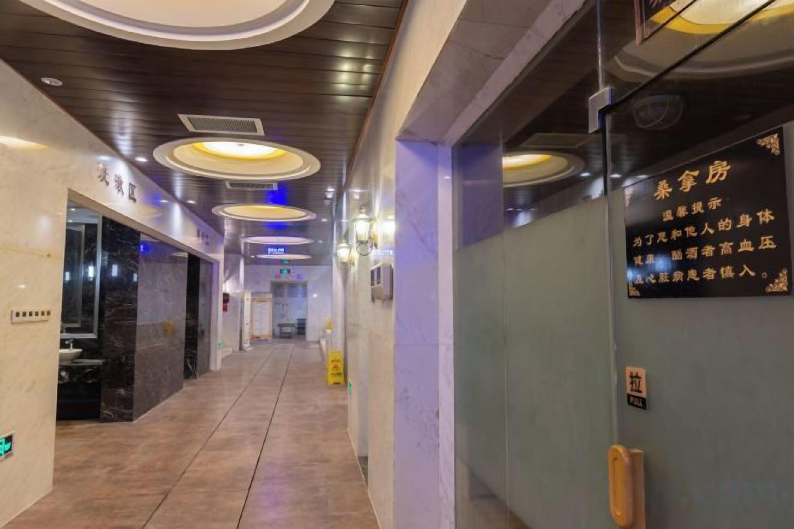 A hotel corridor with a marble floor, recessed lighting, and a sign with text.