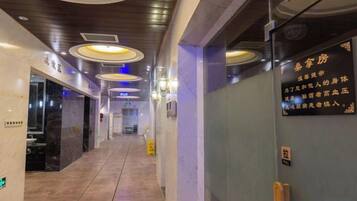 A hotel corridor with a marble floor, recessed lighting, and a sign with text.