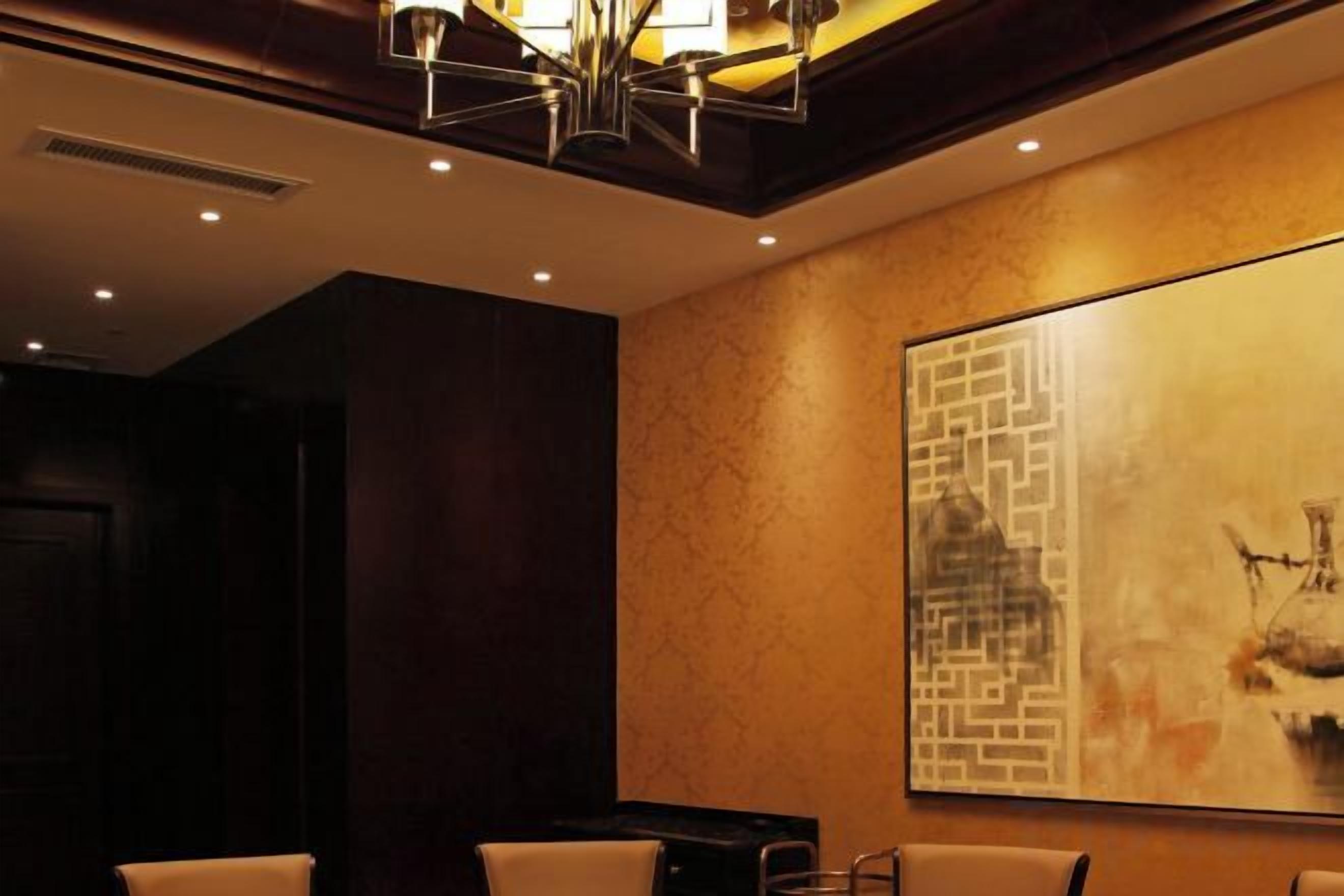 A hotel lobby with a large abstract painting, a chandelier, and a seating area.