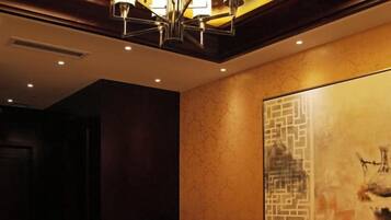 A hotel lobby with a large abstract painting, a chandelier, and a seating area.