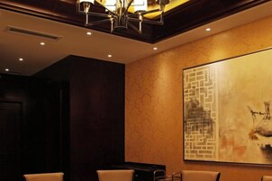 A hotel lobby with a large abstract painting, a chandelier, and a seating area.