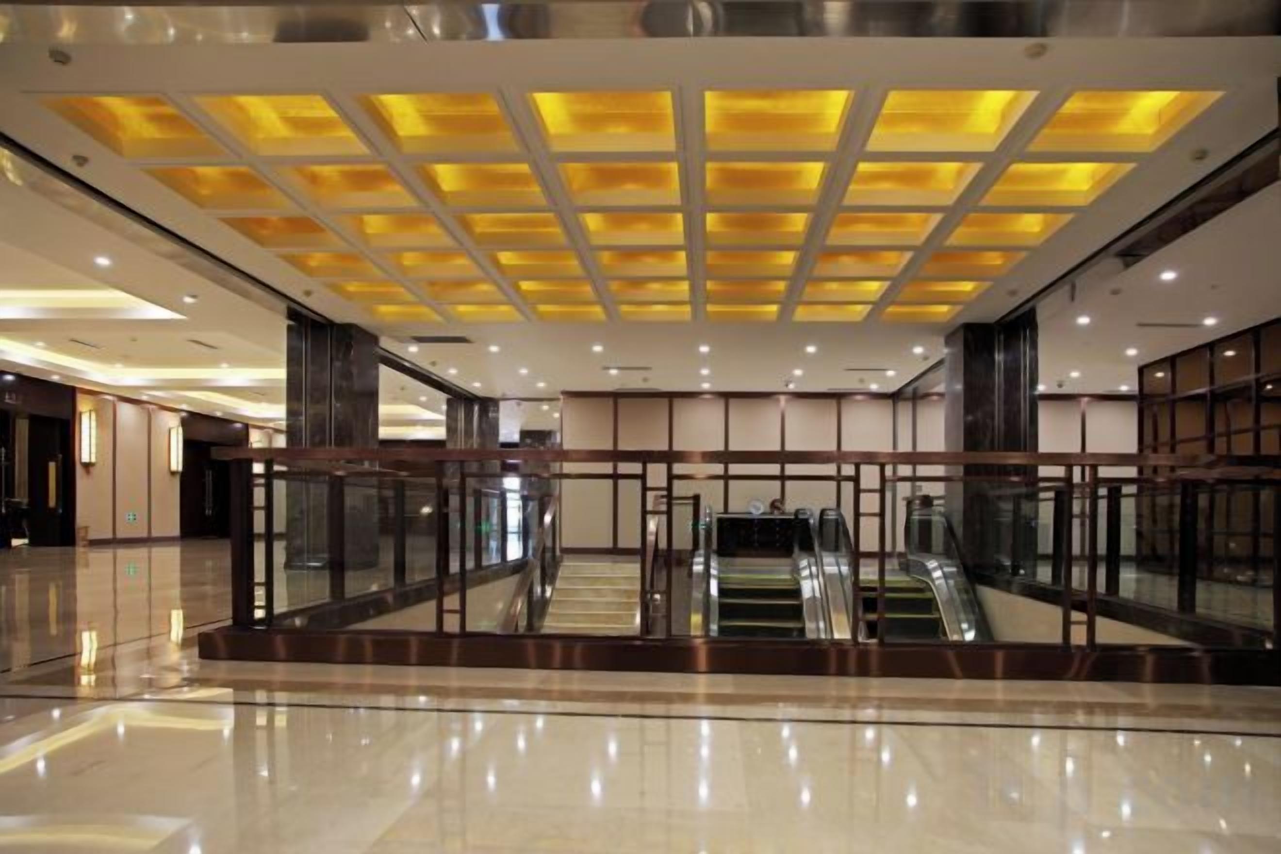 Spaziosa hall con ringhiera in vetro, un'escalatora e un moderno design del soffitto.