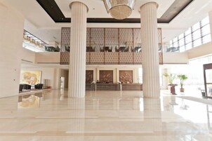 A spacious lobby with high ceilings, large columns, and a mezzanine level.