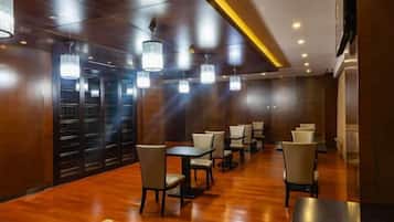 A hotel lobby with wooden flooring, multiple tables and chairs, and pendant lighting.