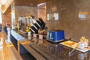 A hotel breakfast area with a marble counter, a blue toaster, and a coffee machine. - Qingcheng Hotel (Qinghe)