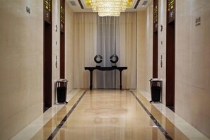 A hotel corridor with a polished floor, a central table, and two trash bins. - Qingcheng Hotel (Qinghe)