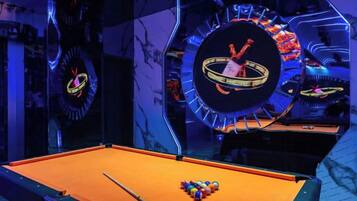 A pool table with balls, a clock, and a neon sign.