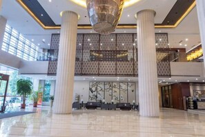 A spacious lobby with high ceilings, large columns, and a modern chandelier. - Qingcheng Hotel (Qinghe)