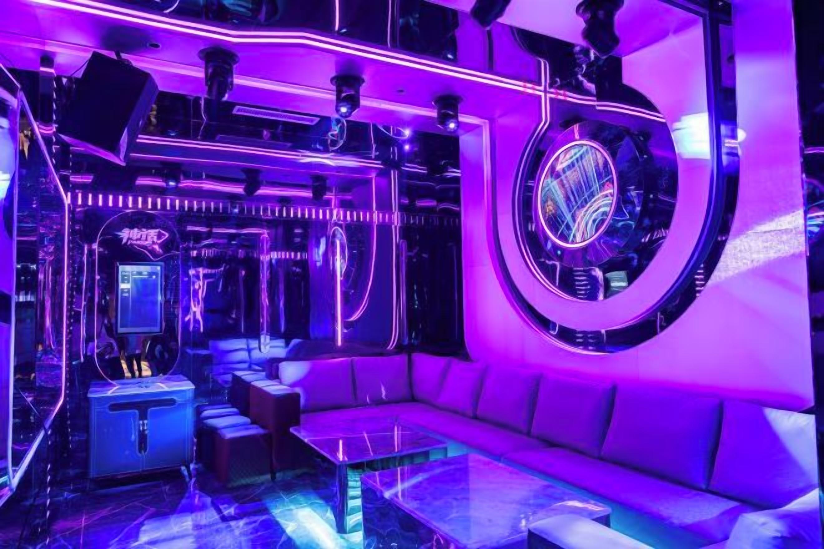 A room with a curved wall, a sofa, a coffee table, and a gaming machine.