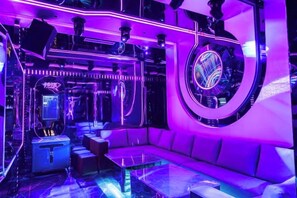 A room with a curved wall, a sofa, a coffee table, and a gaming machine. - Qingcheng Hotel (Qinghe)
