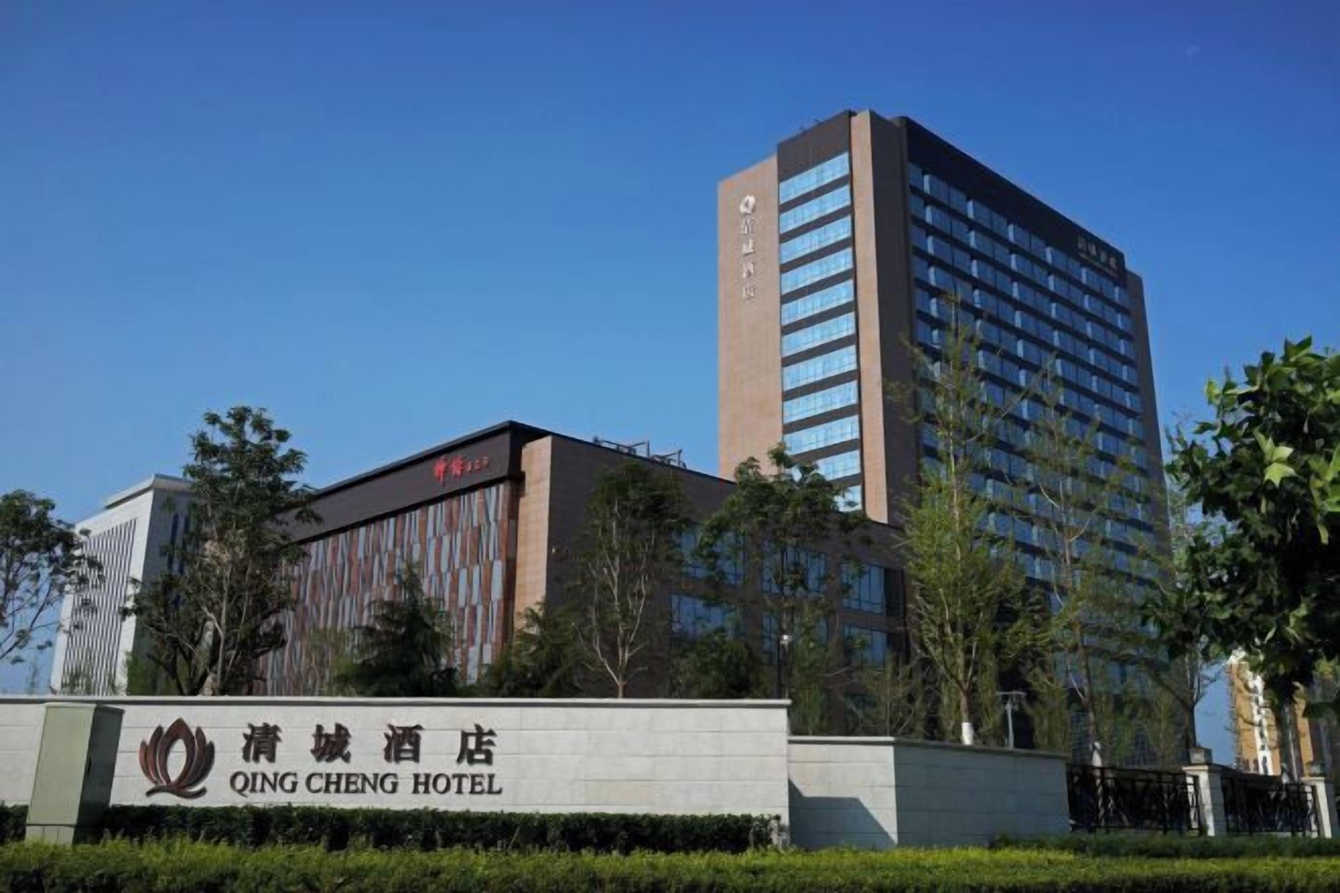 A hotel with a prominent sign, a tall building with many windows, and a clear blue sky.