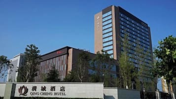 A hotel with a prominent sign, a tall building with many windows, and a clear blue sky.