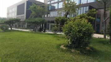 A modern building with a grassy area and trees in front.